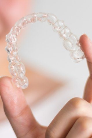 Hand holding an SureSmile clear aligner