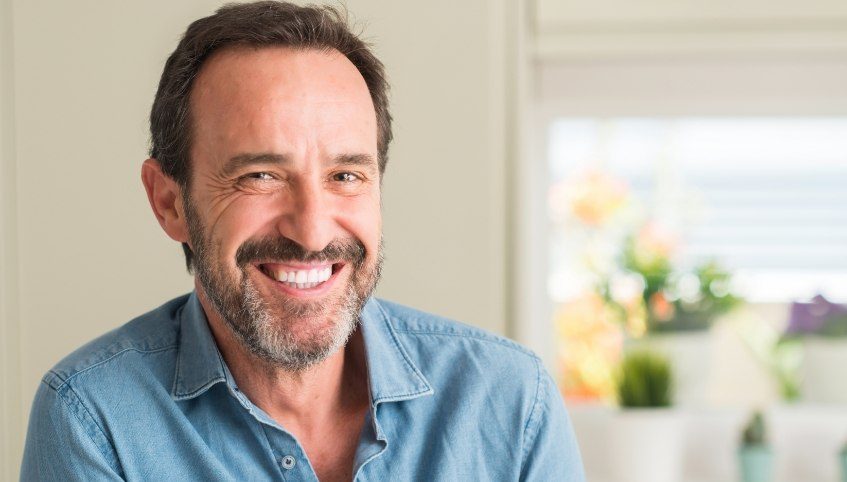 Man in denim shirt smiling with dental implants in Arundel