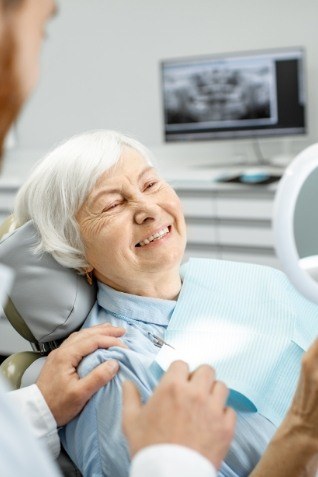 Senior dental patient admiring her smile in mirror