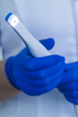 Two gloved hands holding an intraoral camera