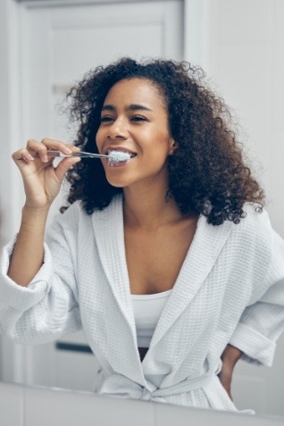 Woman smiling while brushing her teeth