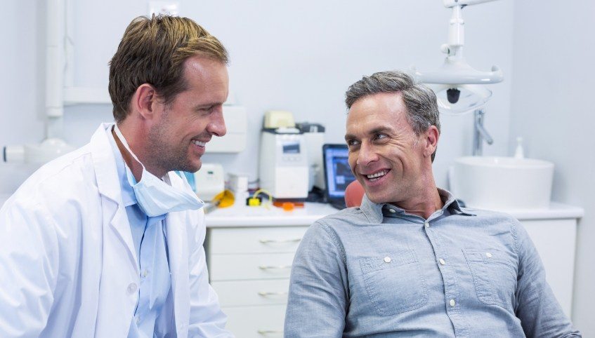 Older man smiling while talking to his Arundel dentist