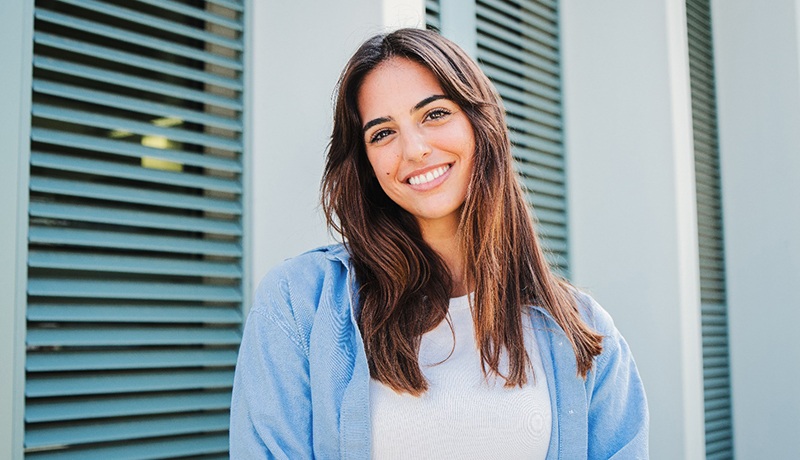 Woman with white teeth smiling while standing outside