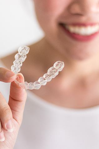 Woman in white shirt holding SureSmile aligner