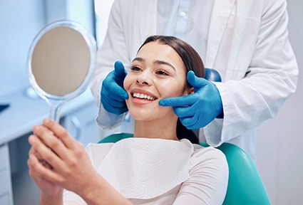 Woman smiling at reflection in handheld mirror