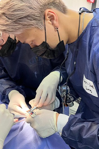 Grey haired dentist with mask treating patient