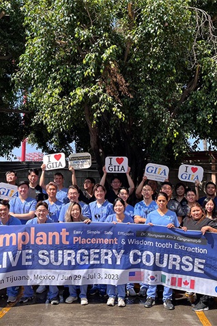 Many dentists holding sign for live surgery course