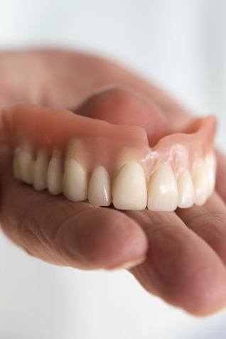 Hand holding a full denture