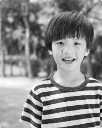 Young boy in striped shirt smiling outdoors