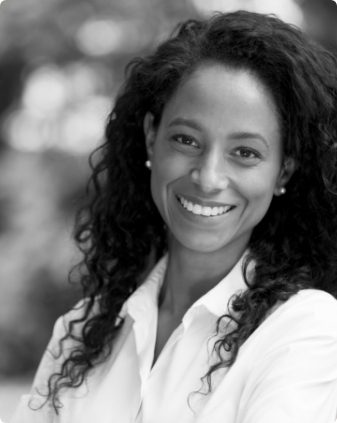 Woman with curly black hair grinning outdoors