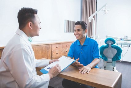 Dentist and patient conversing at desk