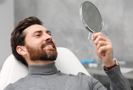 Dental patient using mirror to admire his new restorations