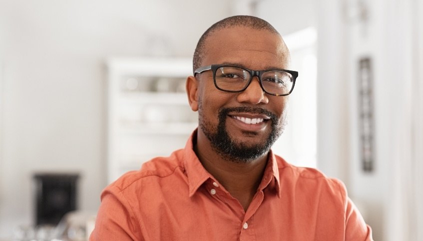 Man in orange shirt smiling after restorative dentistry in Arundel